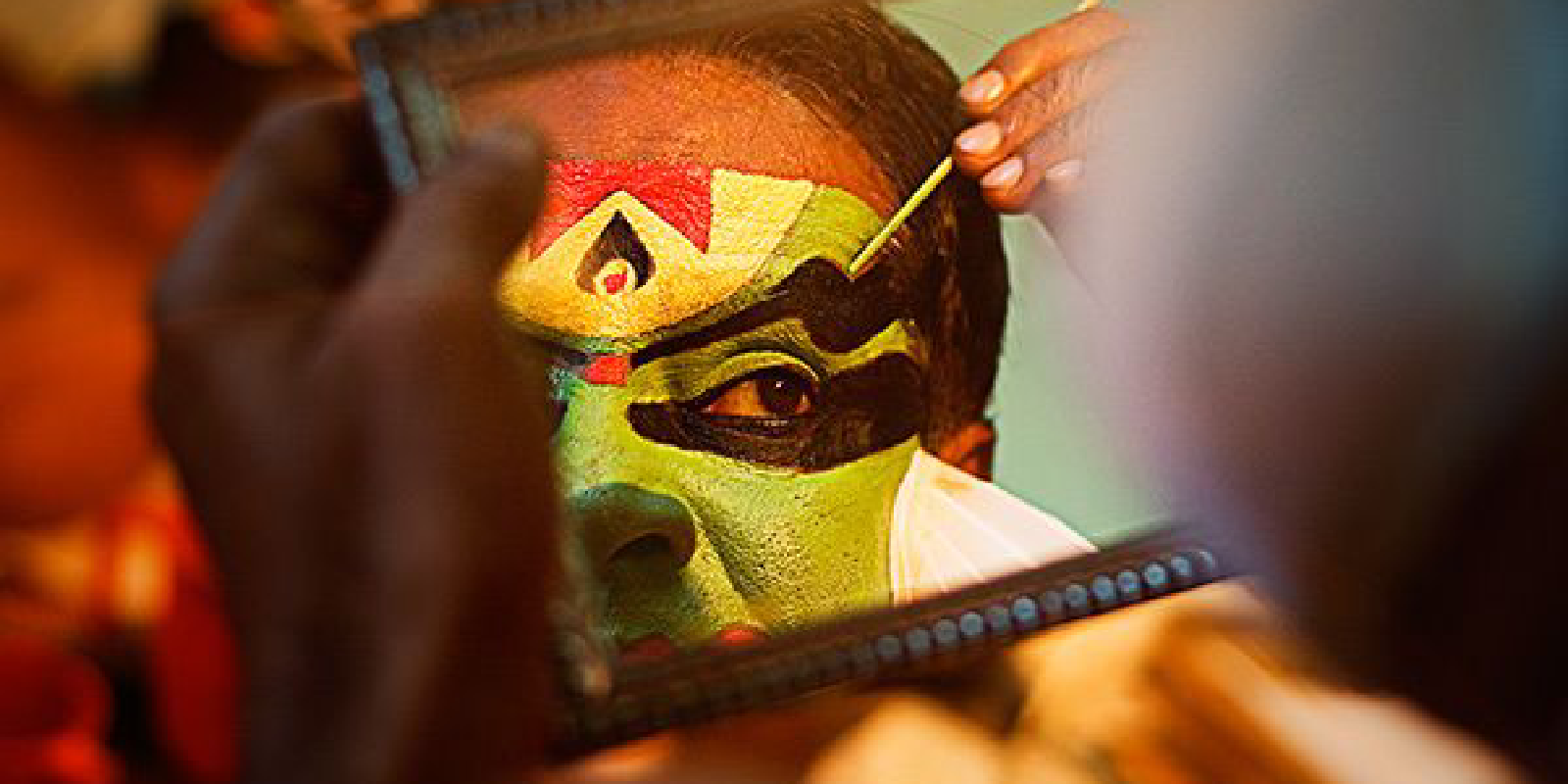 Close-up of a Kathakali face paint performer’s vibrant face paint, with bold colors and intricate patterns.