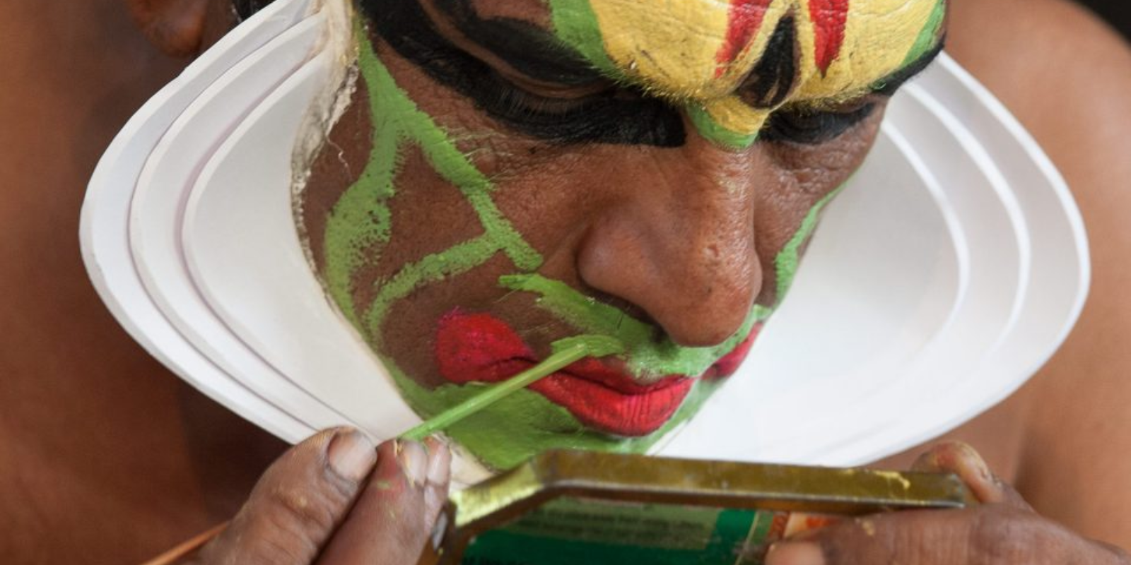 Close-up of a Kathakali face paint performer’s vibrant face paint, with bold colors and intricate patterns.