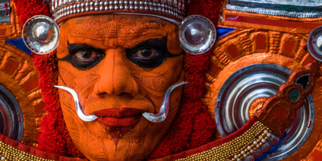 Theyyattam performer in vibrant costume enacting a powerful ritual dance filled with energy and tradition.