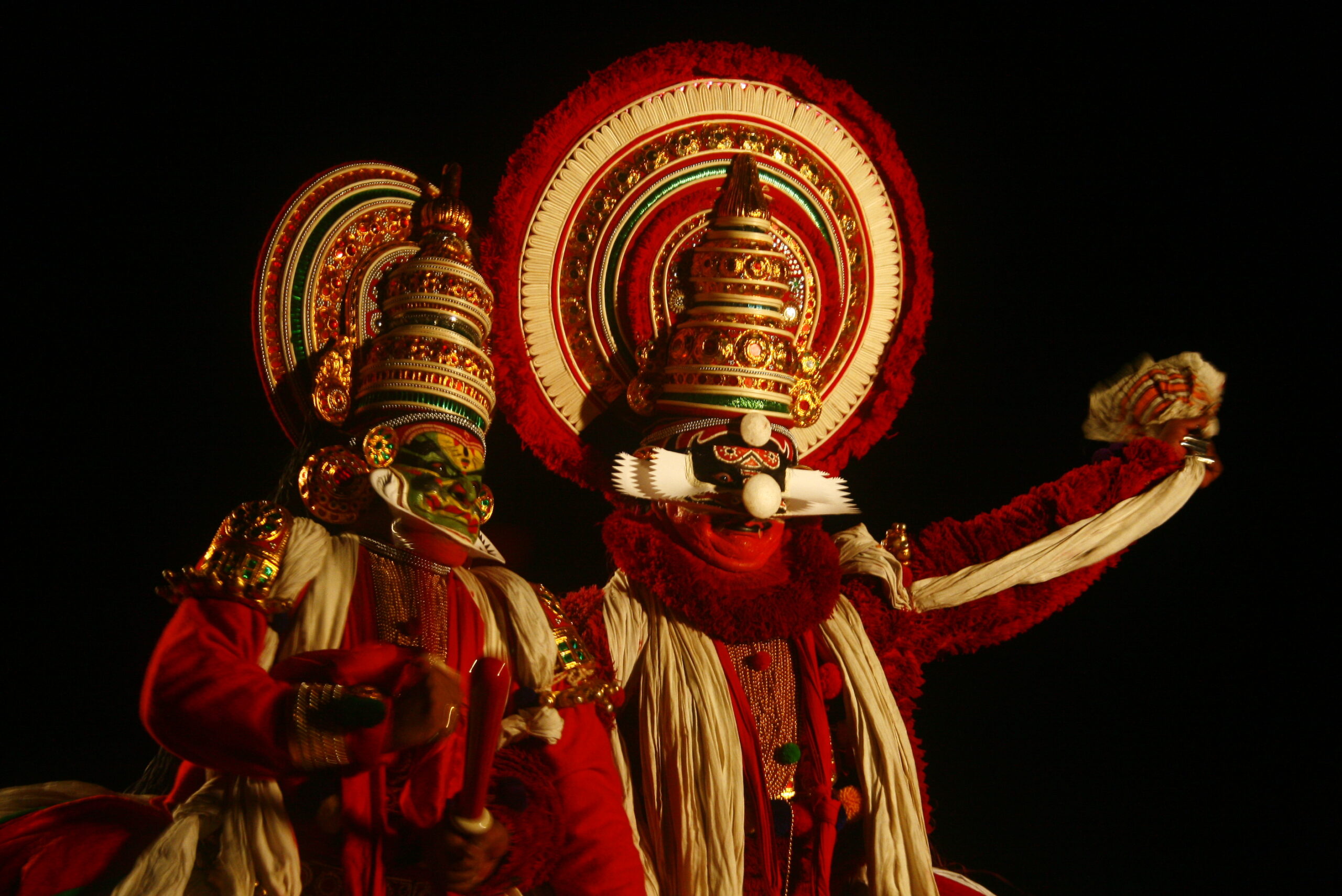 Kathakali performance in vibrant costumes and makeup, enacting a dramatic scene on stage