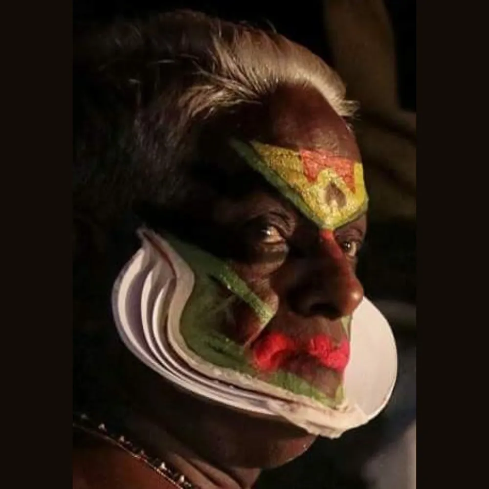 Traditional Kathakali dancer wearing a vibrant costume with elaborate headgear and face makeup