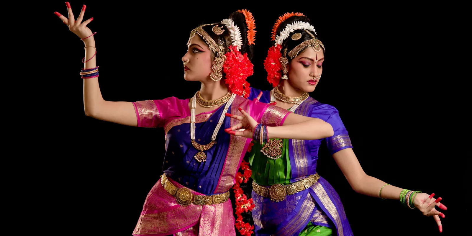 Young Kuchipudi dancer in vibrant costume performing traditional Indian dance move with expressive gestures.