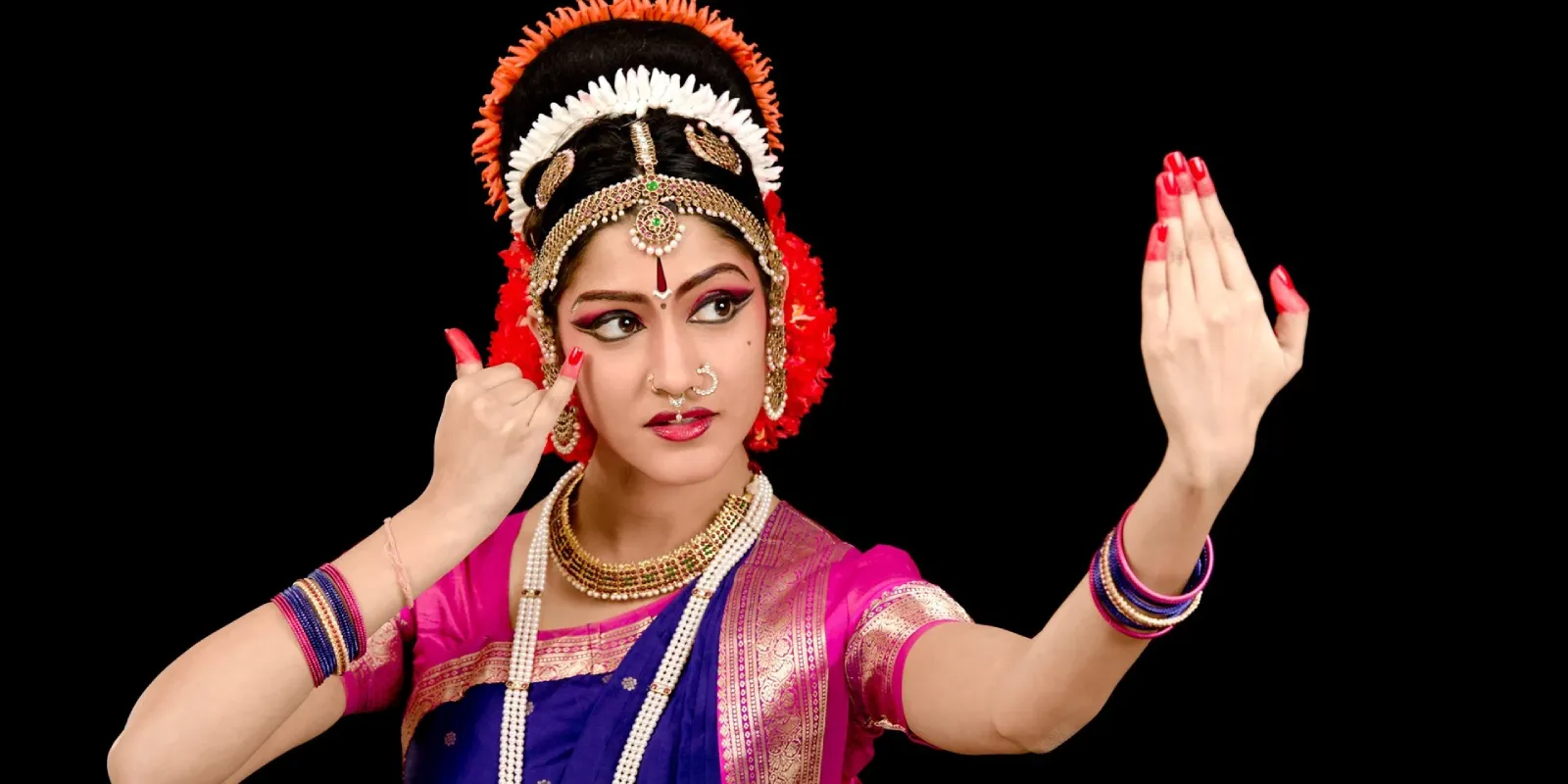 Young Kuchipudi dancer in vibrant costume performing traditional Indian dance move with expressive gestures.