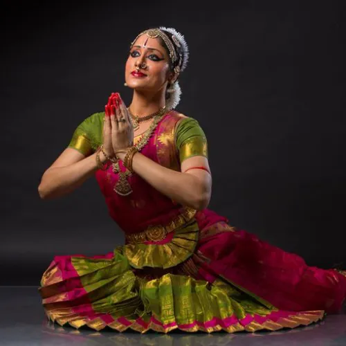 Young Kuchipudi dancer in vibrant costume performing traditional Indian dance move with expressive gestures.