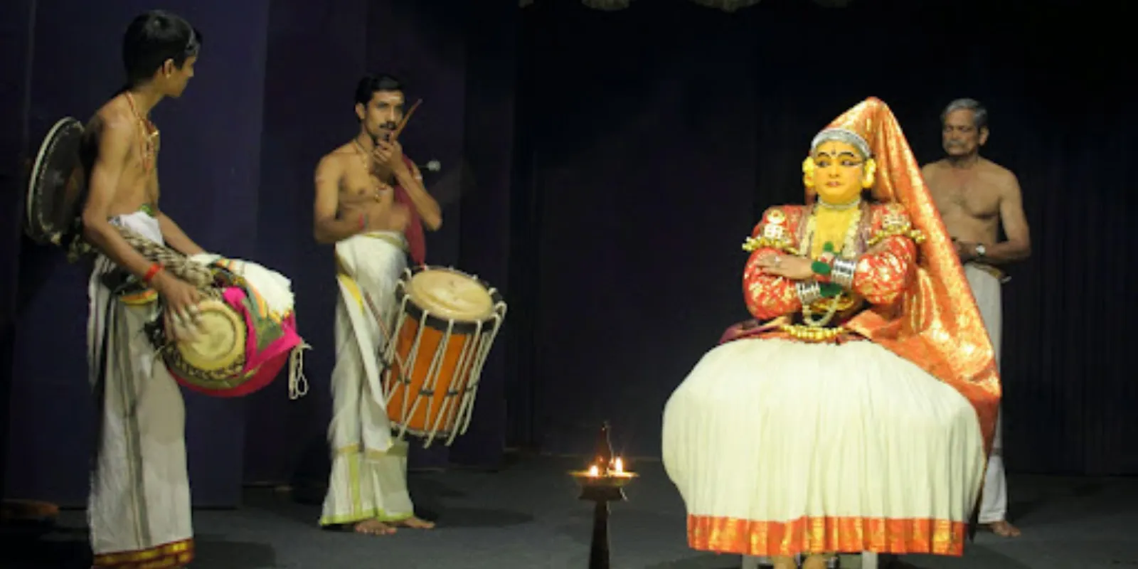 Musicians performing Kathakali music with traditional instruments, setting the rhythm for the dance.