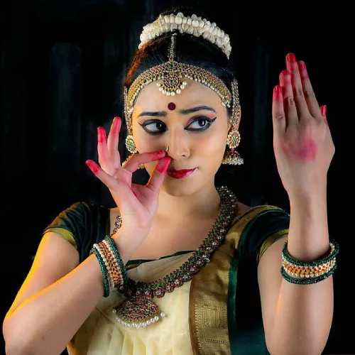 Graceful Mohiniyattam dancer in traditional attire performing with expressive hand gestures.