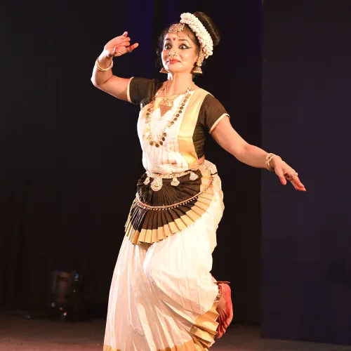 Graceful Mohiniyattam dancer in traditional attire performing with expressive hand gestures.