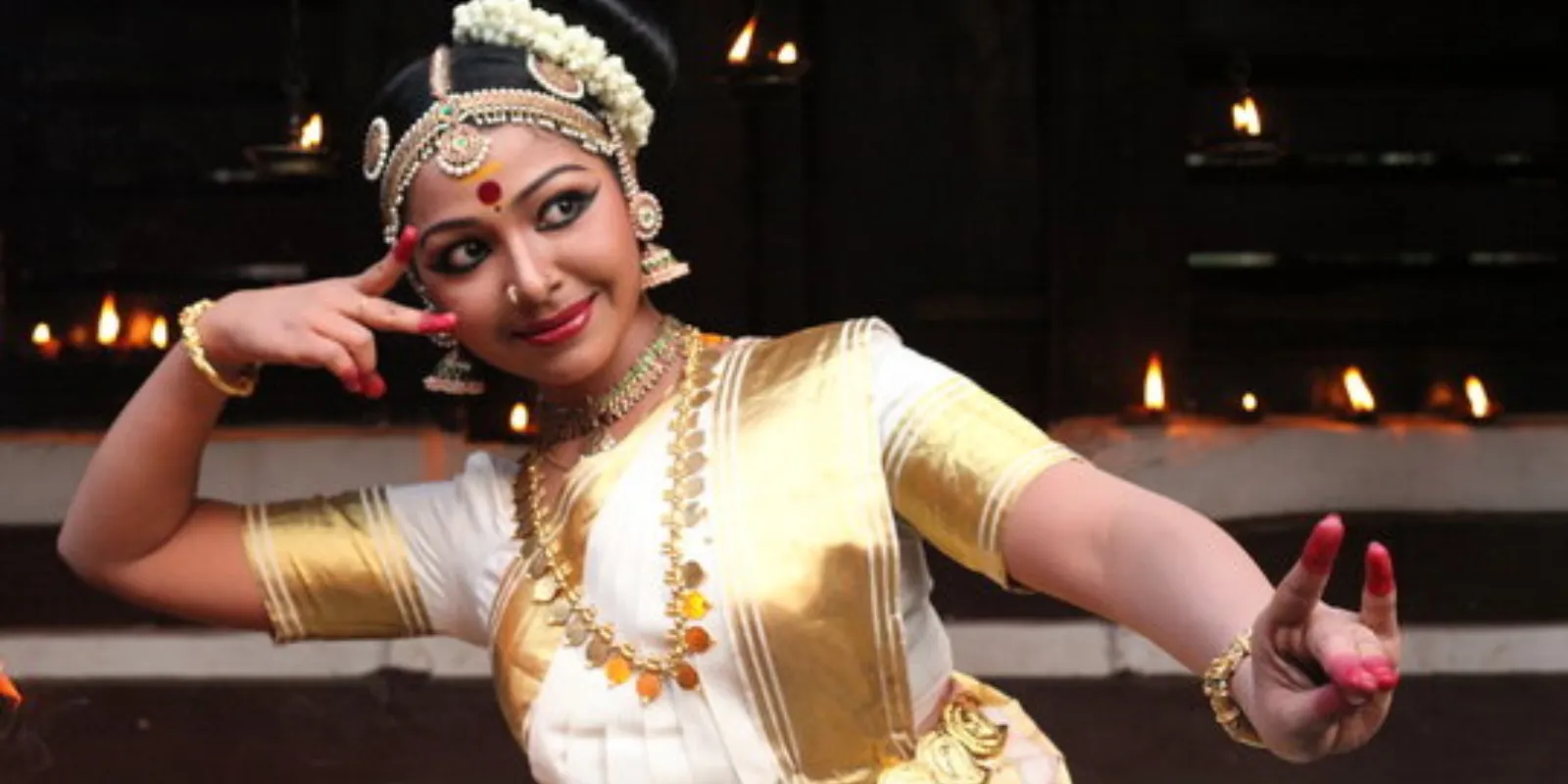 Graceful Mohiniyattam dancer in traditional attire performing with expressive hand gestures.