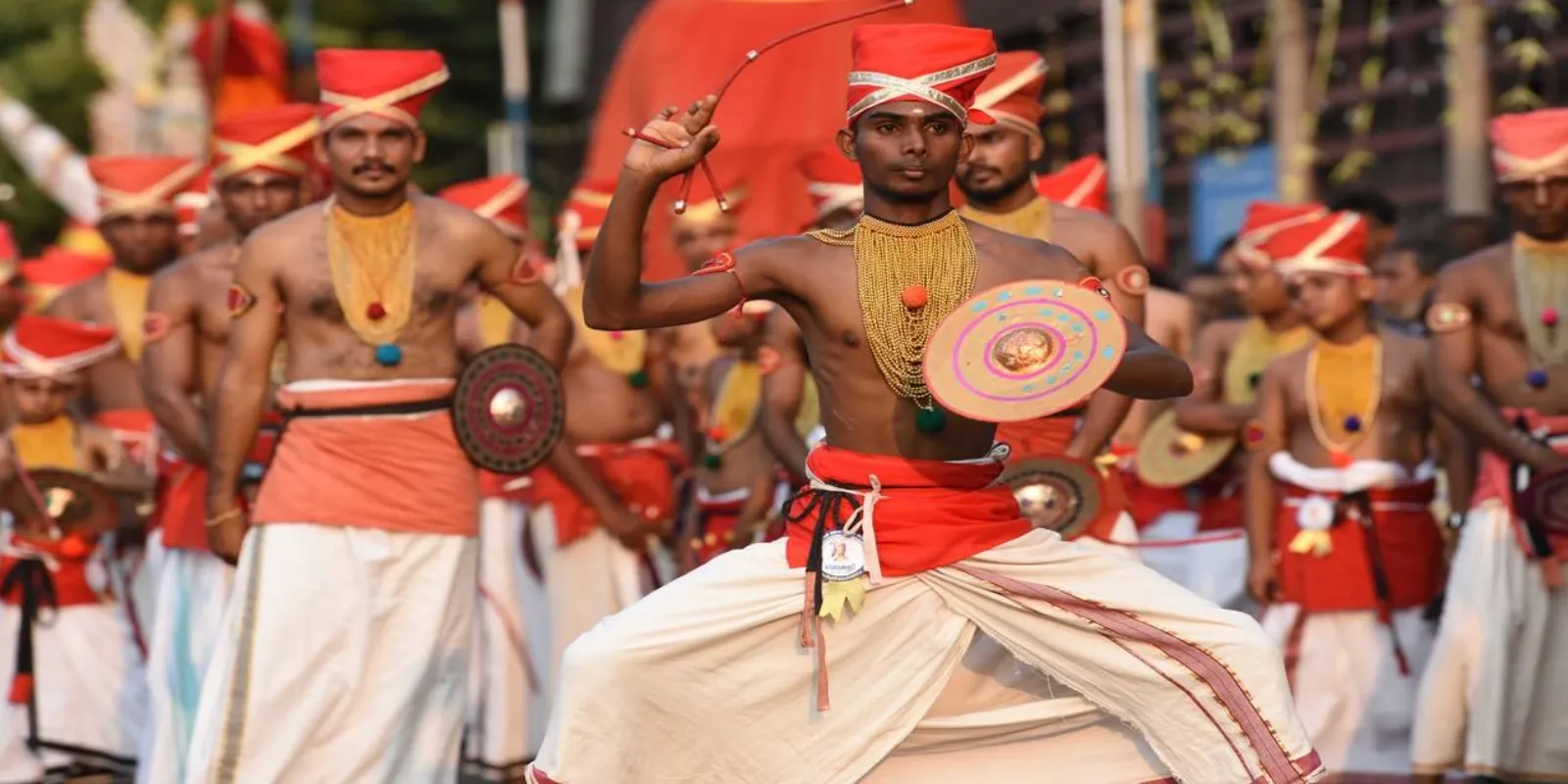 Velakali performers in traditional attire showcasing synchronized, warrior-like dance movements.