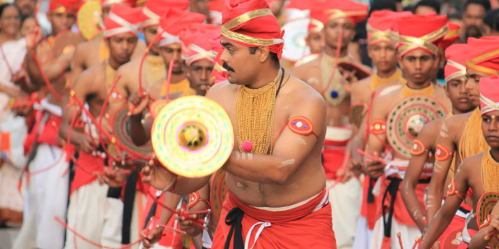 Velakali performers in traditional attire showcasing synchronized, warrior-like dance movements.