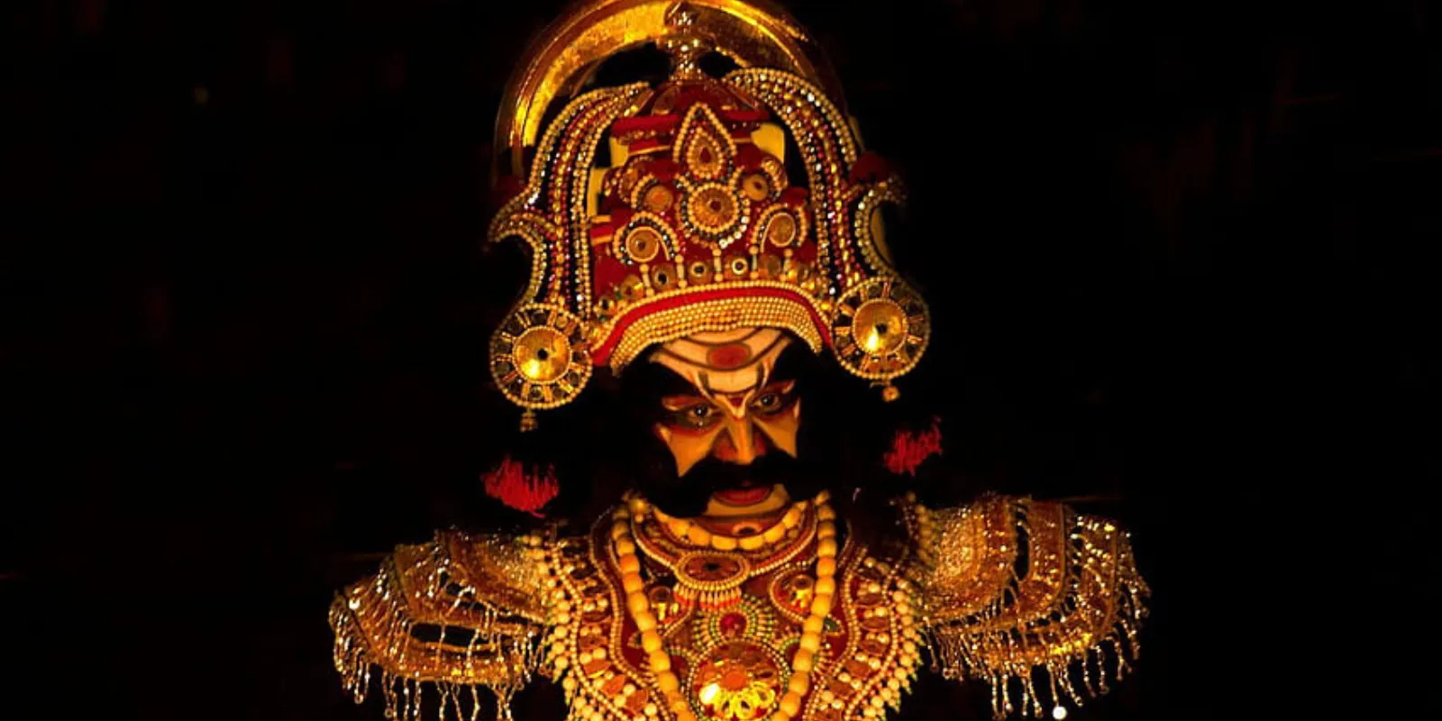 Yakshaganam performer in colorful costume showcasing dramatic expressions and lively dance on stage